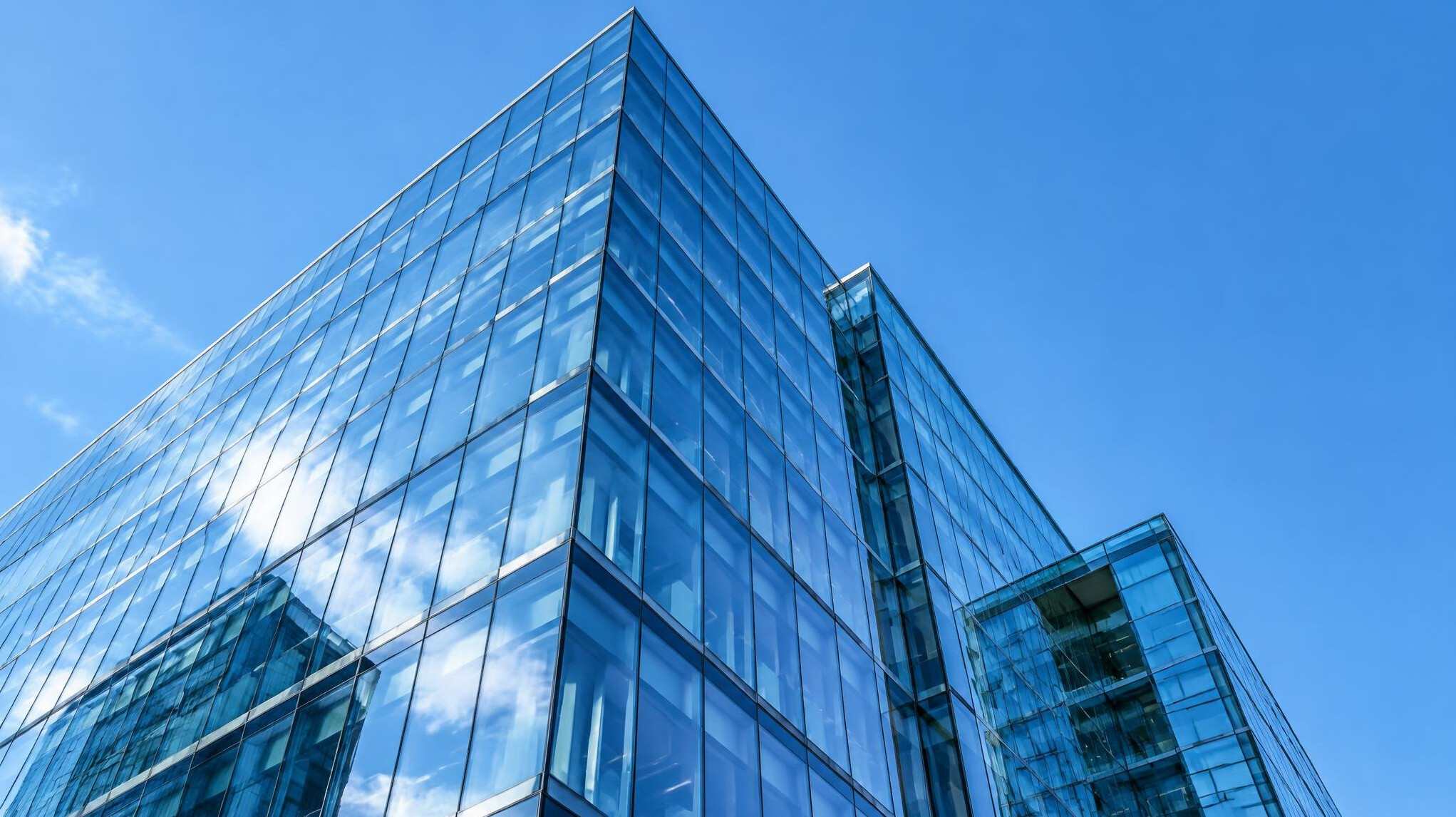 Modern glass office building against a blue sky